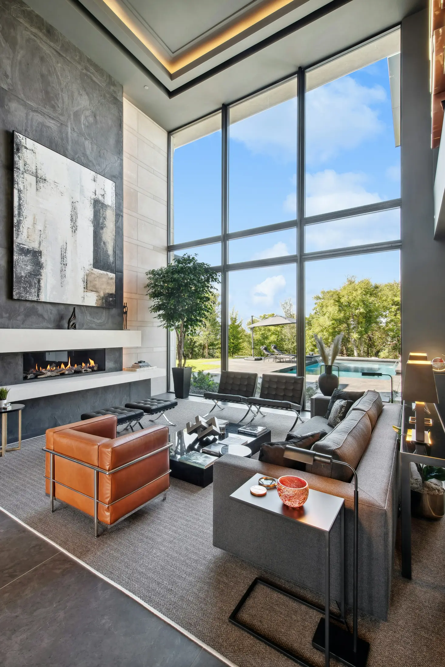 Double-height living room with floor-to-ceiling glazing, stone fireplace and tailored leather seating